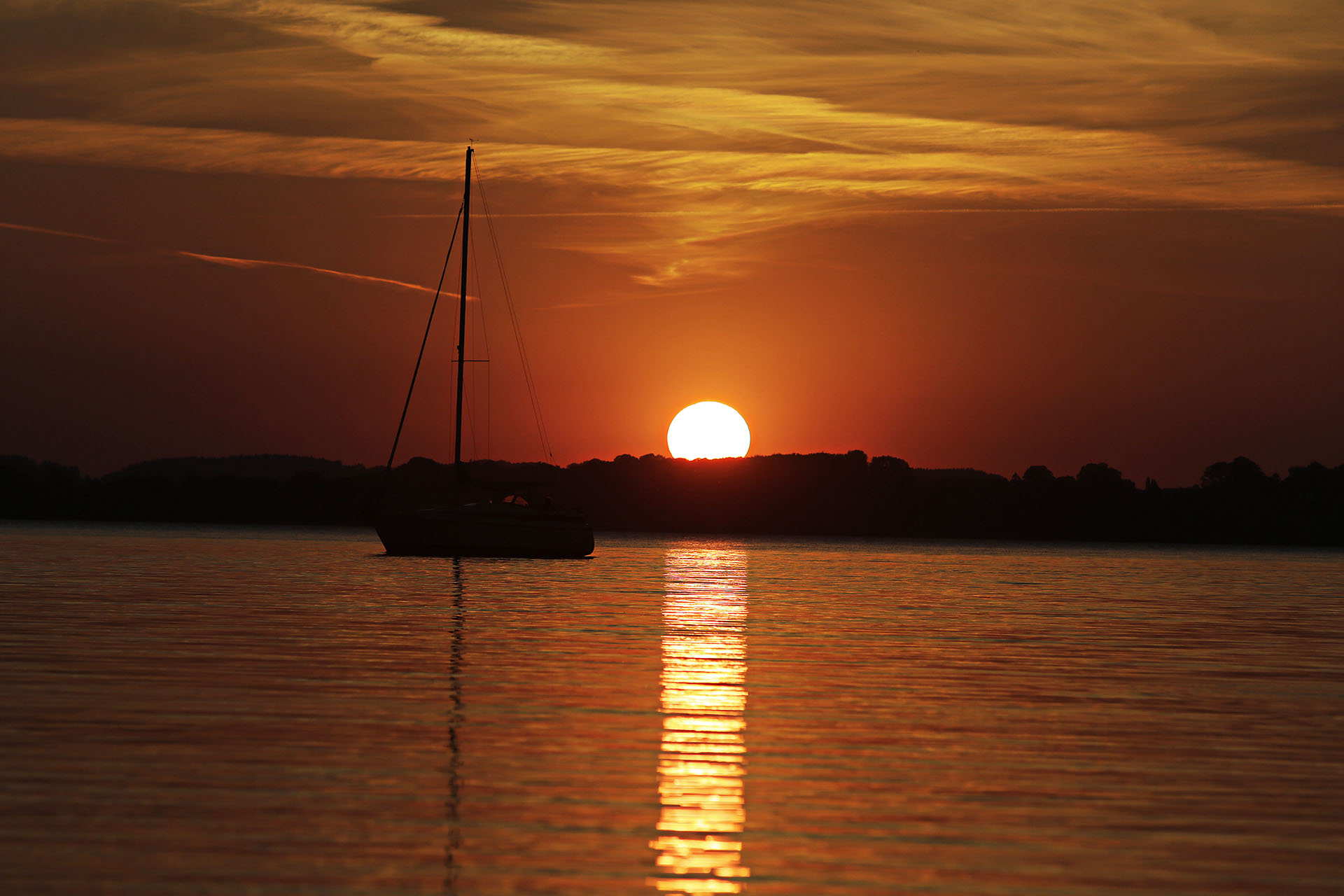 Segelboot bei Sonnenuntergang auf ruhigem Wasser